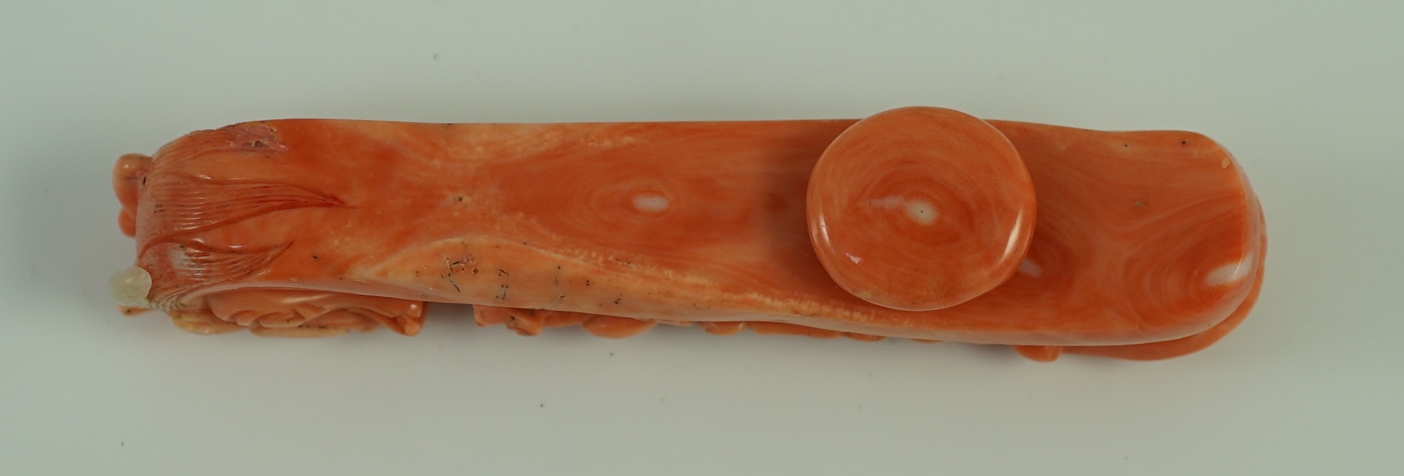 A rare Chinese coral 'dragon' belt hook 18th/19th century, 9.2 cm long, small loss to dragon horn, wood stand